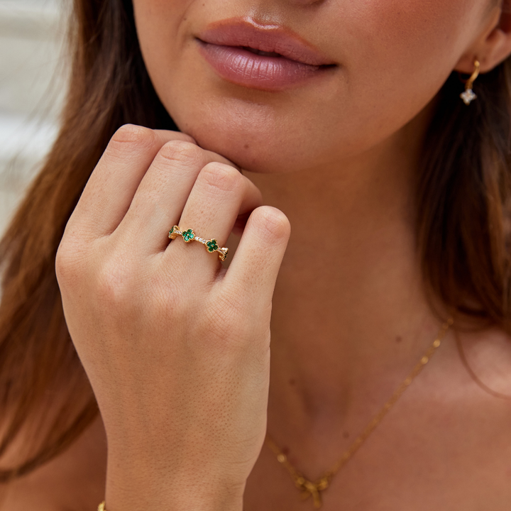Annika – Zlacený prsten s květinovými detaily a smaragdovým prvkem.