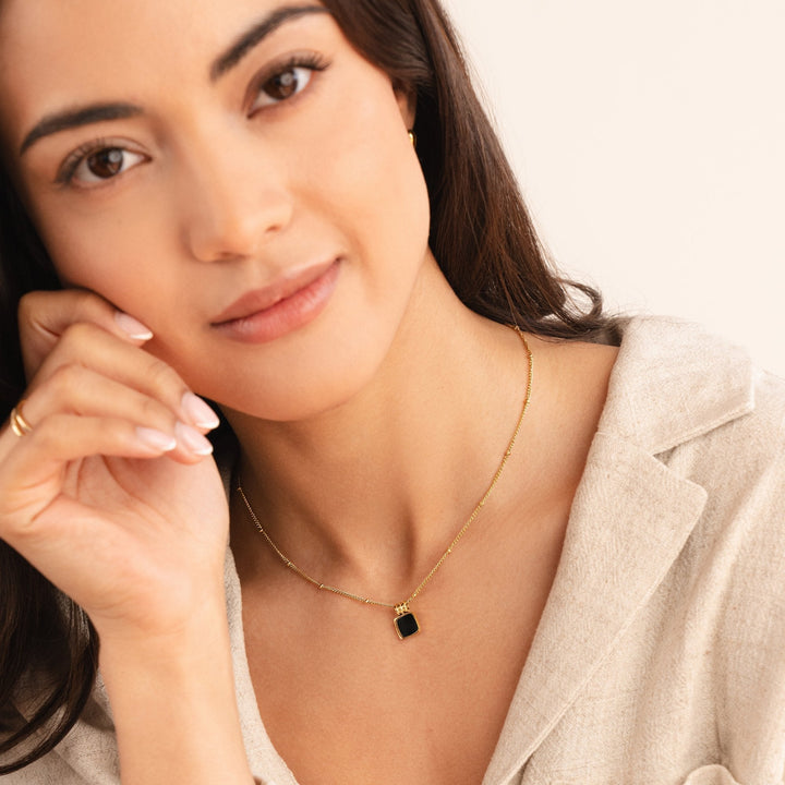 Selina – Zlatý náhrdelník s tmavým kamenem.
